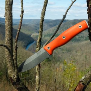 The Micron MK-4, featuring an orange handle, is lodged between tree branches with a scenic river and forested hills in the background.